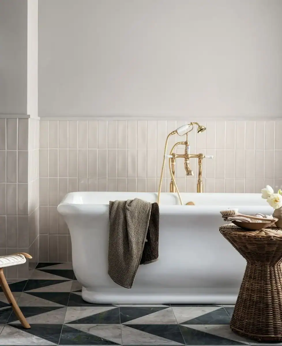Classic freestanding bathtub in elegant white bathroom with herringbone floor tiles