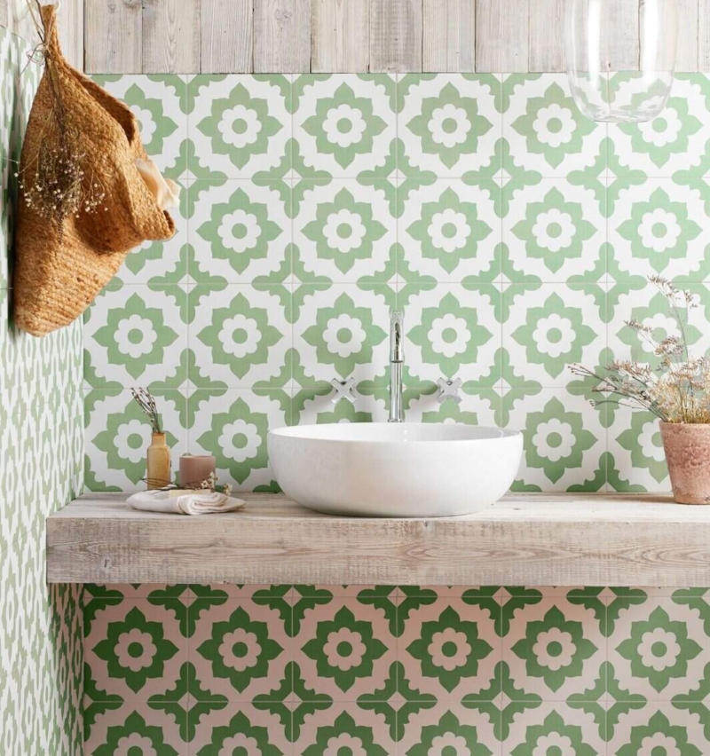 Green patterned bathroom tiles behind a white countertop basin