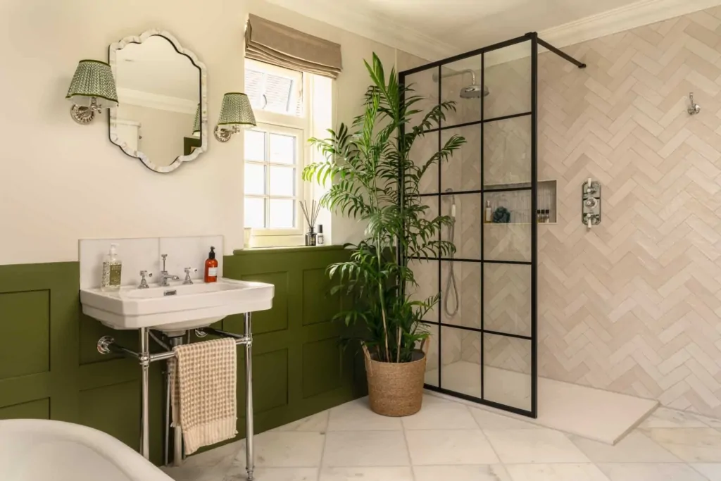 Bathroom with green panelling, black framed shower screen and indoor plants