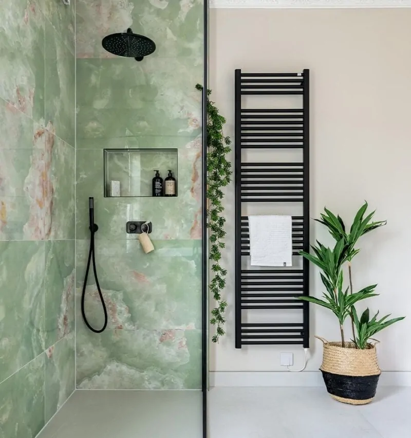Green tiled walk-in shower with black fittings and heated towel rail