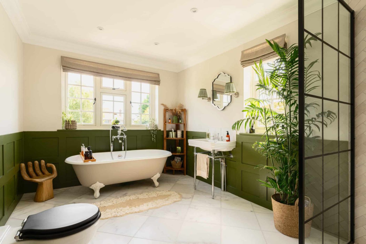Bright bathroom with freestanding bath, green panelled walls and indoor plants