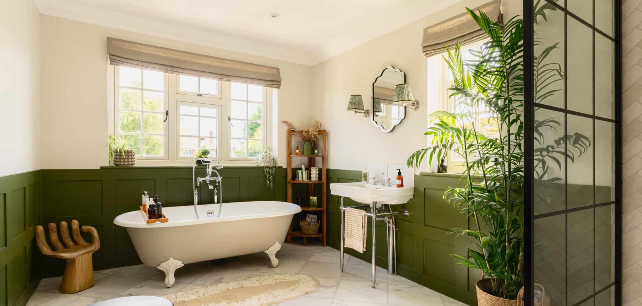 Bright bathroom with freestanding bath, green panelled walls and indoor plants