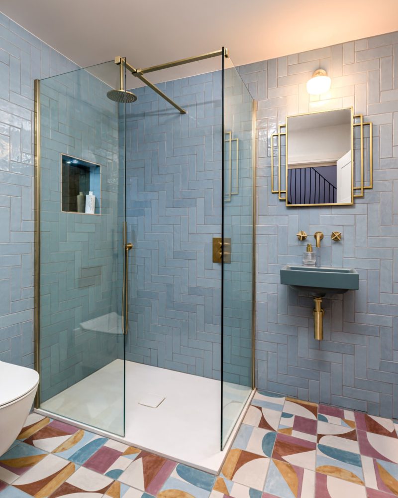 Luxury walk-in shower with glass screen, blue tiles and brass fittings