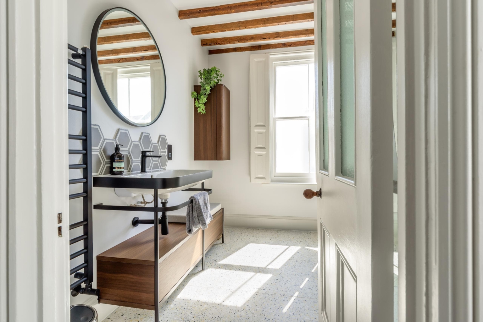 Bright contemporary bathroom with round mirror, dark vanity and timber details