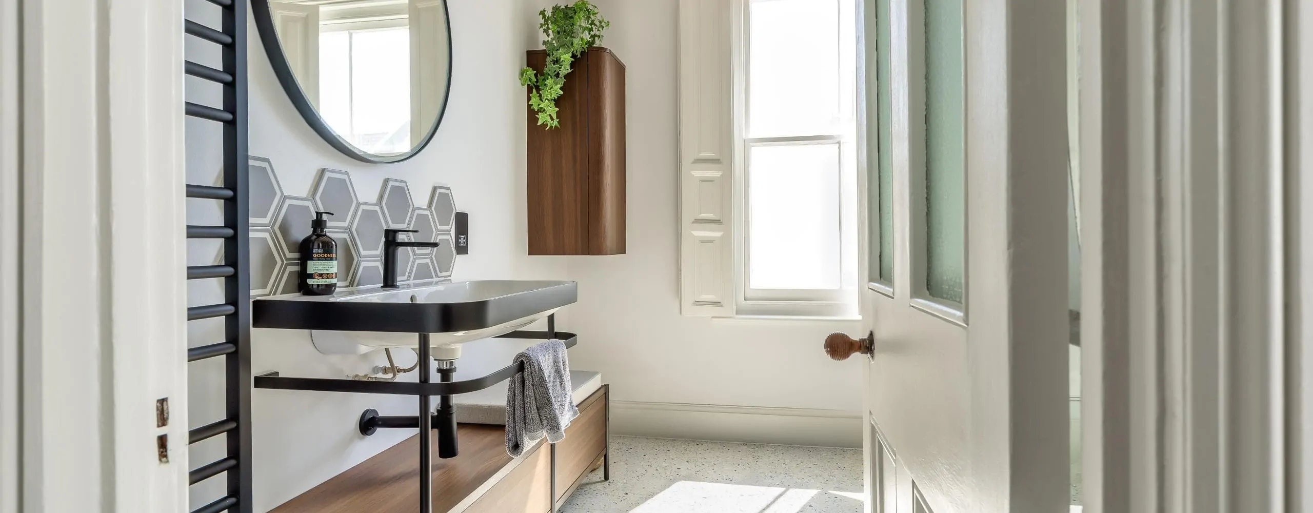 Bright contemporary bathroom with round mirror, dark vanity and timber details