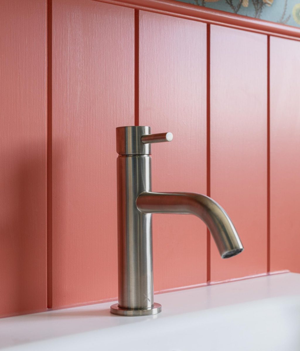 Contemporary basin tap against bold coral pink bathroom tiles