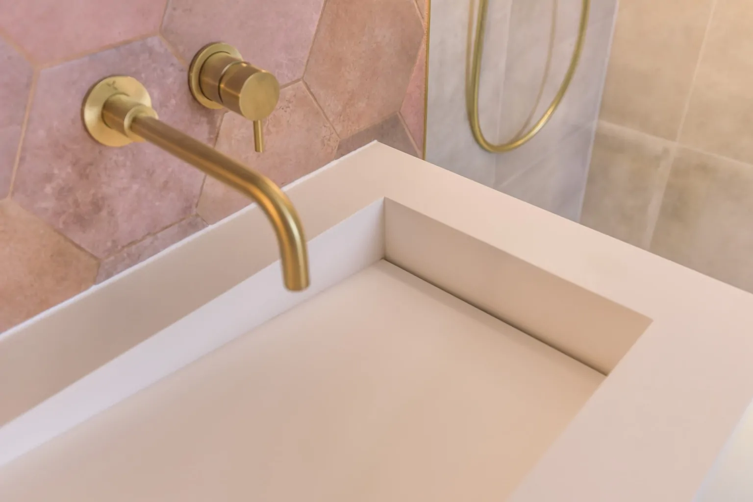 Brushed brass tap with pale pink basin and marble effect surface