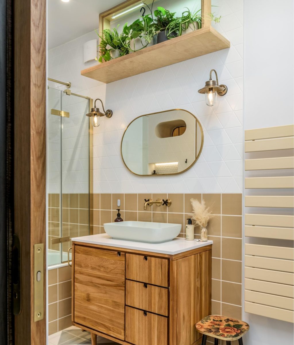 Contemporary bathroom vanity with oval mirror, gold fittings and neutral tiles