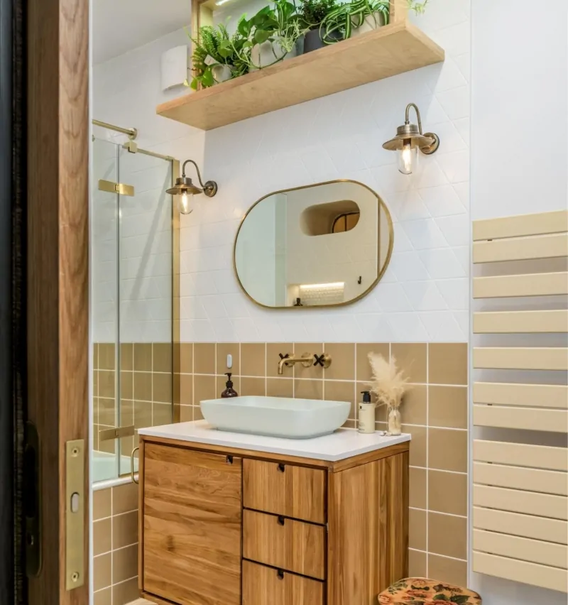 Contemporary bathroom vanity with oval mirror, gold fittings and neutral tiles