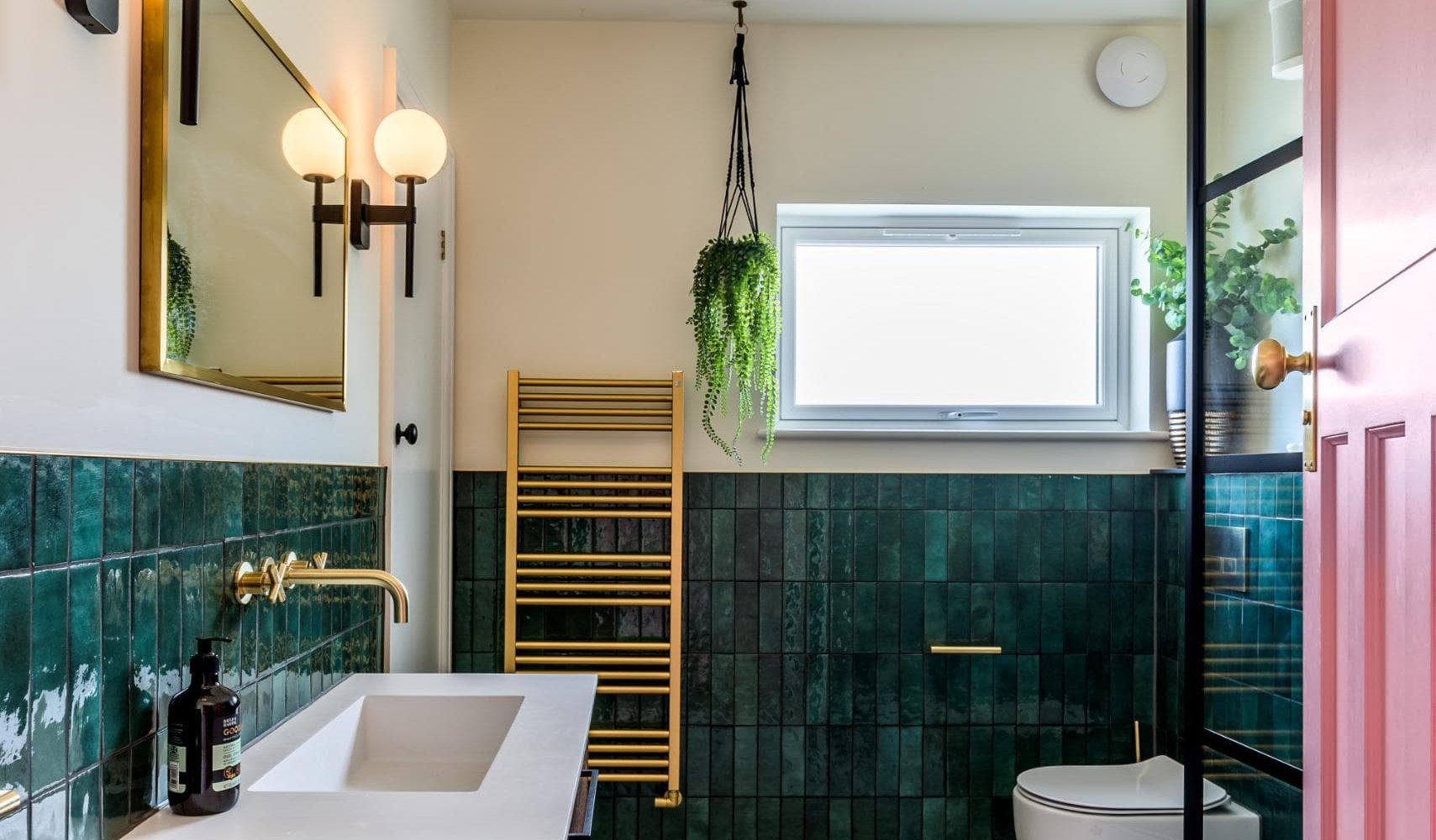 Green tiled bathroom with wall mirror, black lighting and natural light