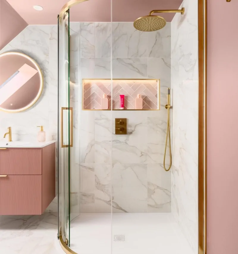 Marble effect shower area with brass fittings beneath a pink sloping ceiling
