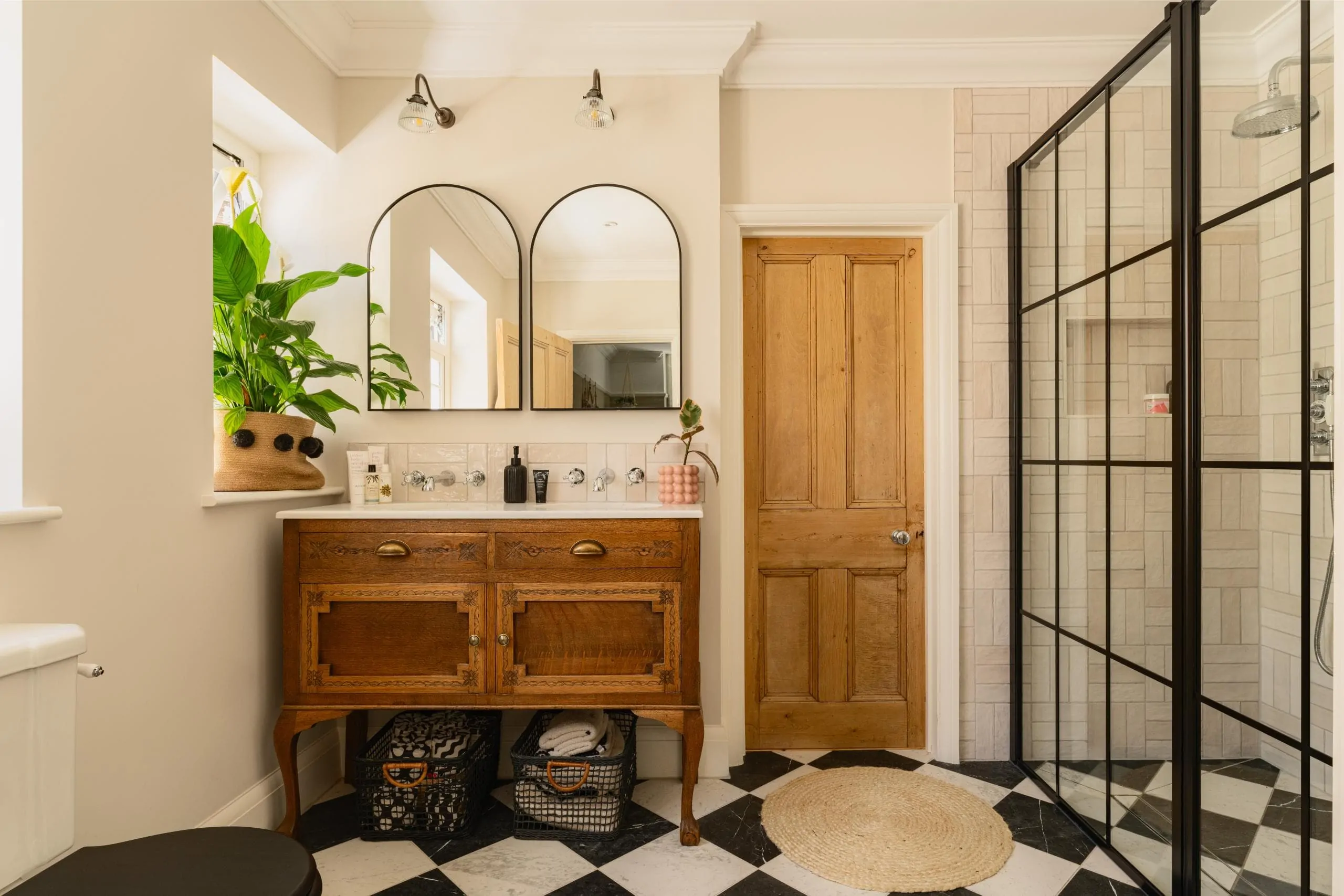 Luxury double vanity with arched mirrors, timber cabinetry and indoor plants
