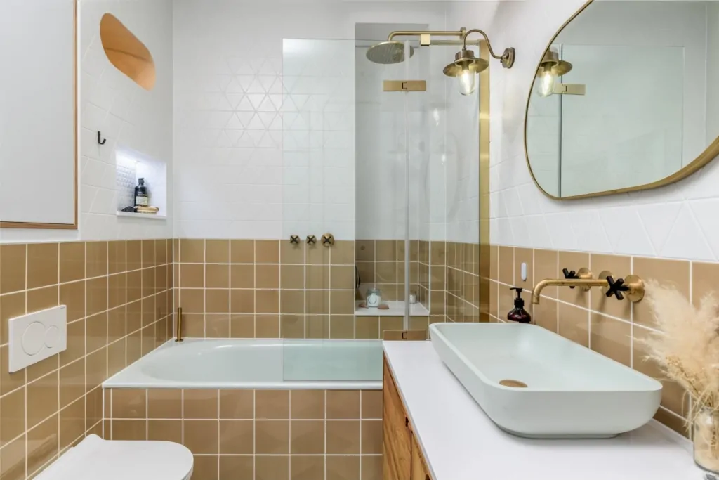 Neutral walk-in shower with glass screen, gold fittings and bespoke storage