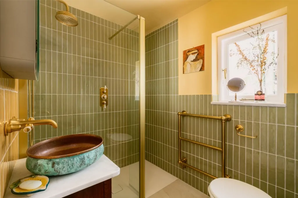Contemporary green tiled shower with brass fittings and heated towel rail