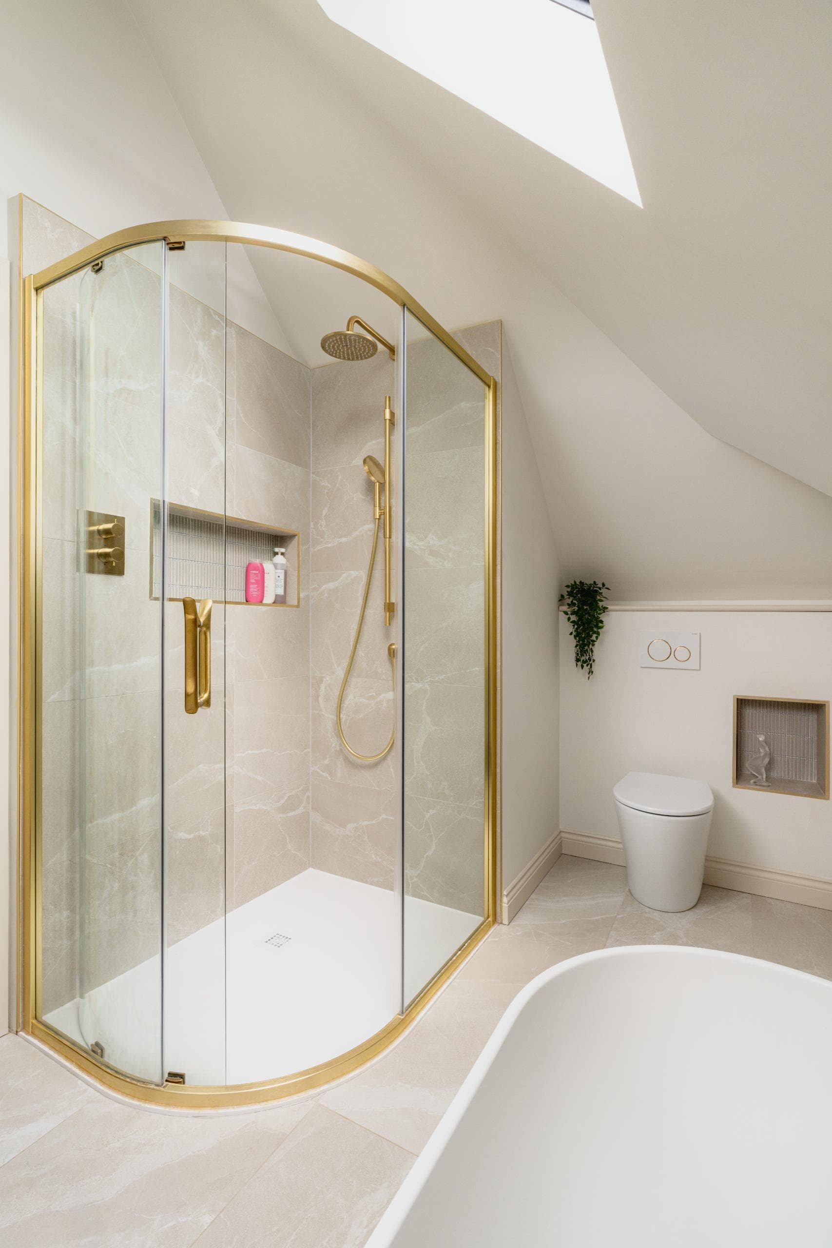 Luxury shower area with glass screen, brass fittings and neutral tiles