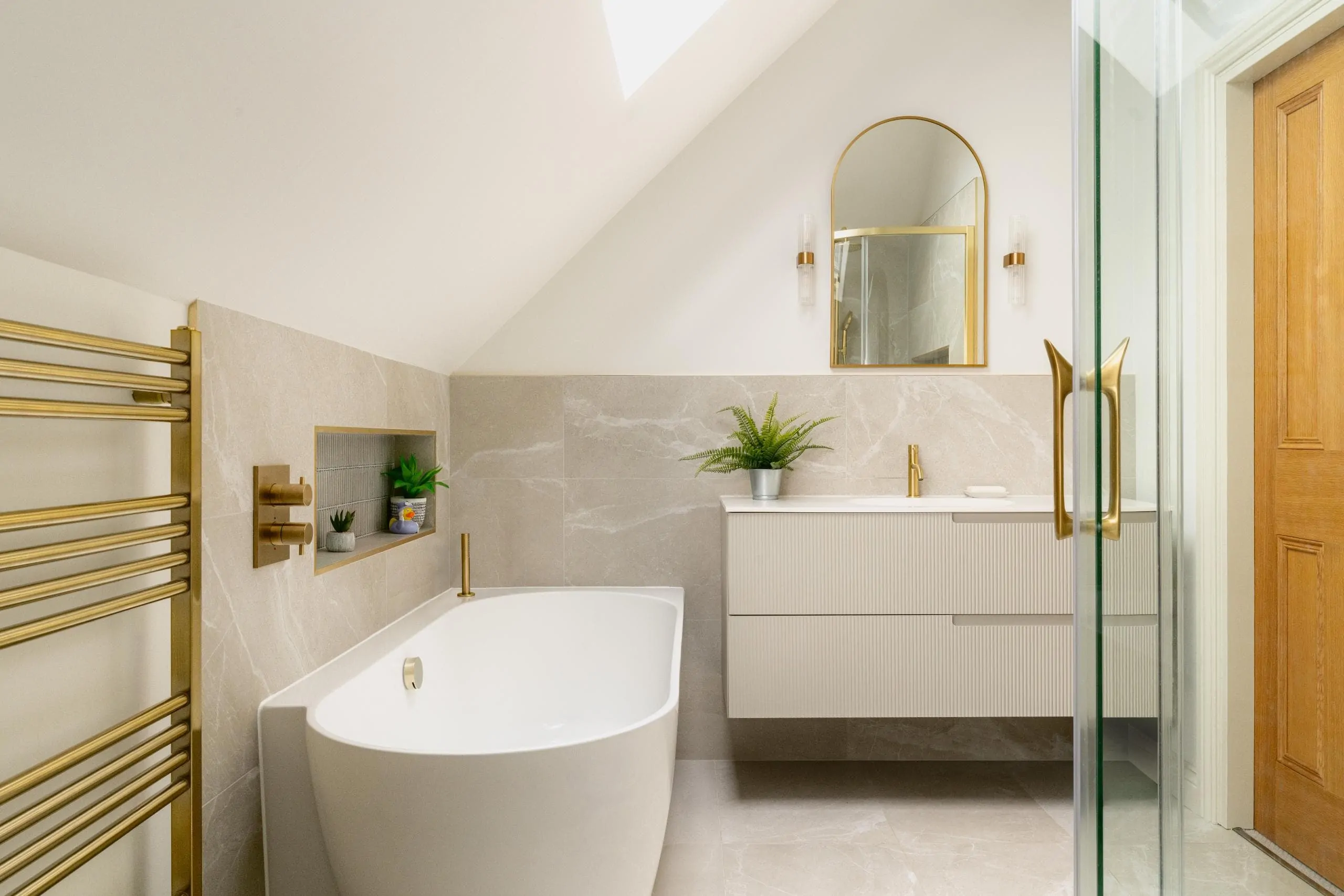 Luxury bathroom with arched mirror, glass shower and neutral finishes