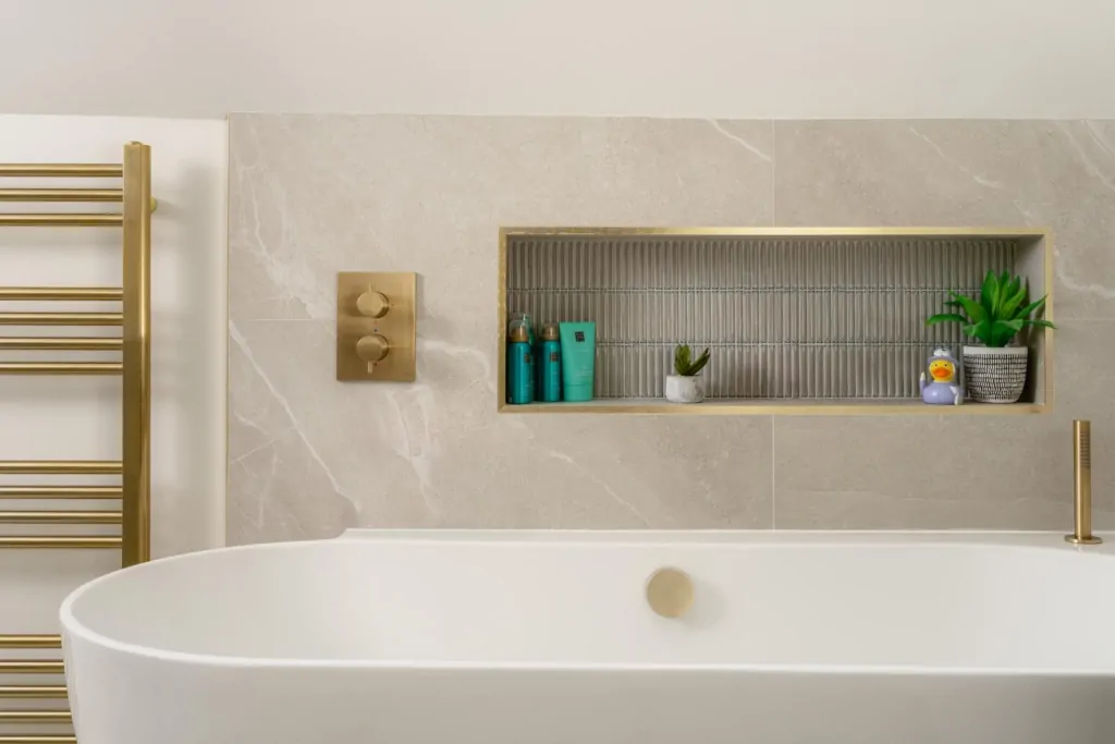 Recessed bathroom storage niche with neutral stone tiles and toiletries
