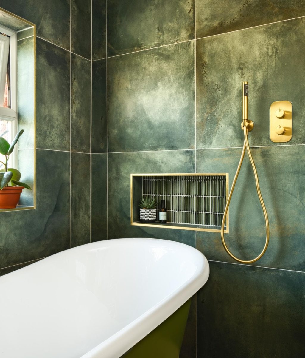 Luxury bathroom with green marble effect tiles, bath and brass heated towel rail