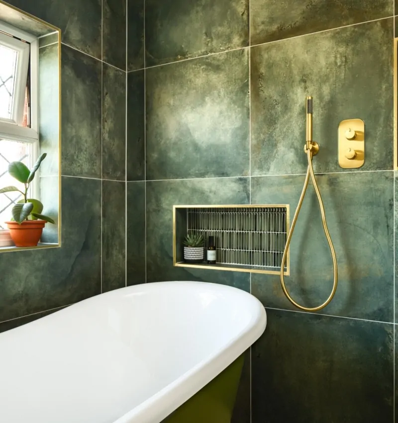 Luxury bathroom with green marble effect tiles, bath and brass heated towel rail