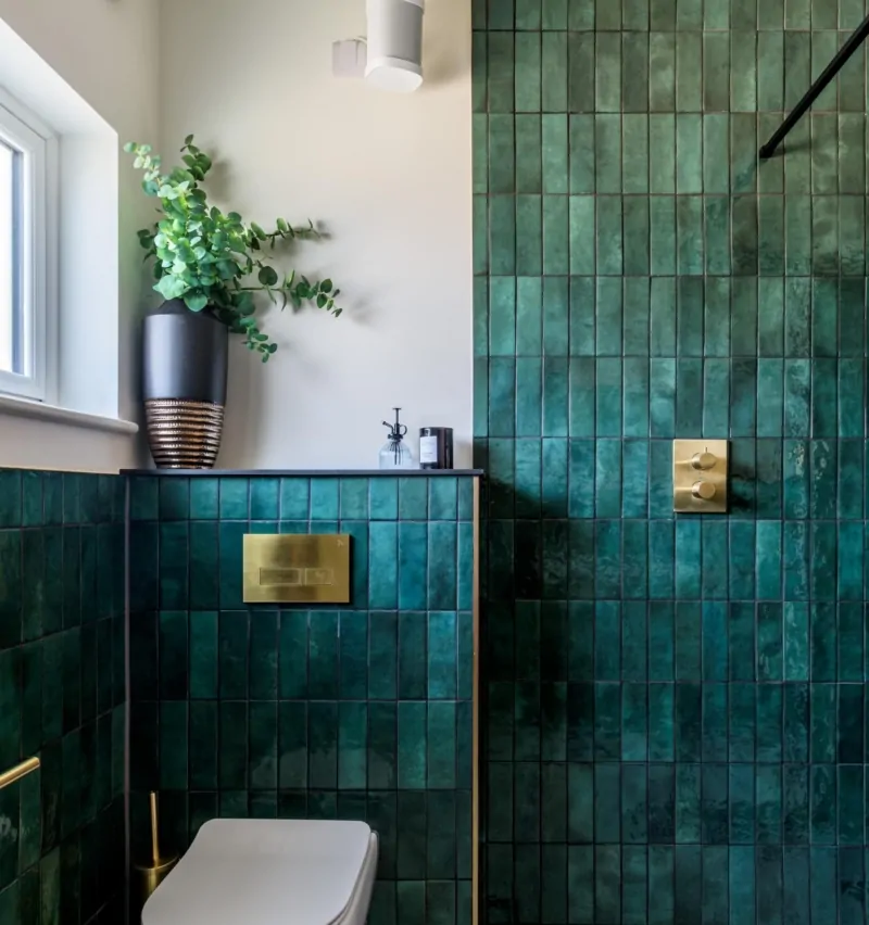 Contemporary bathroom with rich green tiles, natural light and potted greenery