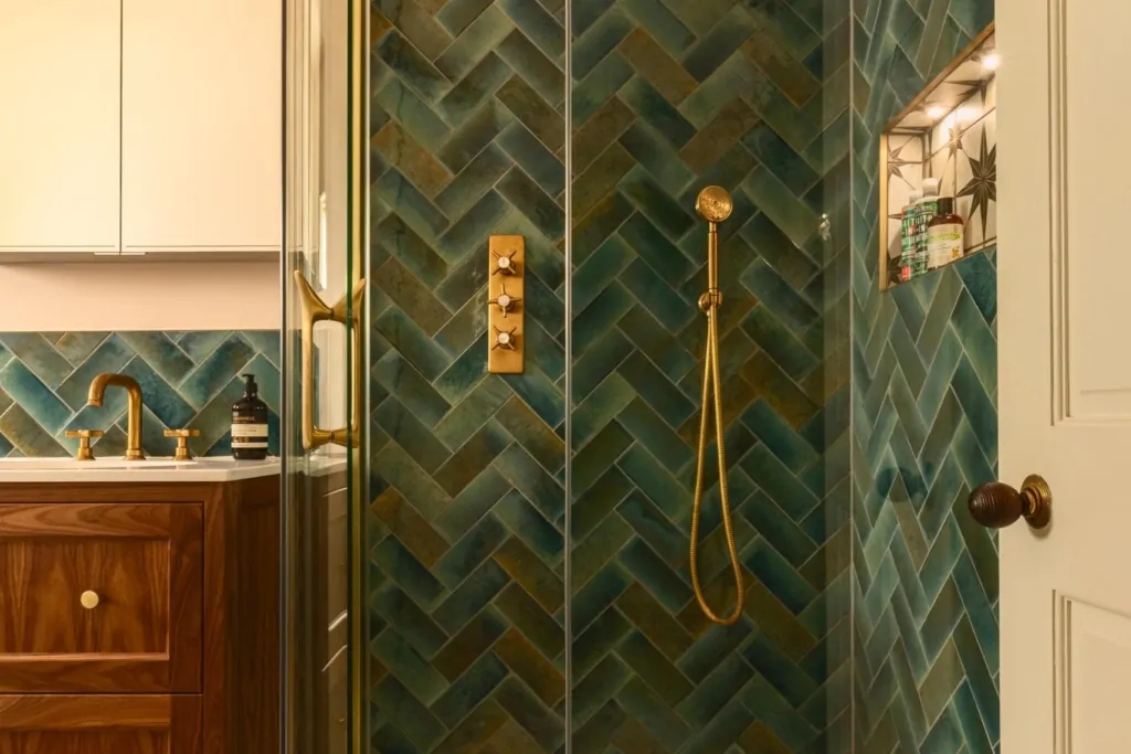 Dark green herringbone shower tiles with brushed brass fittings