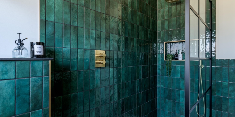 Contemporary shower area with deep green tiles and brass fittings