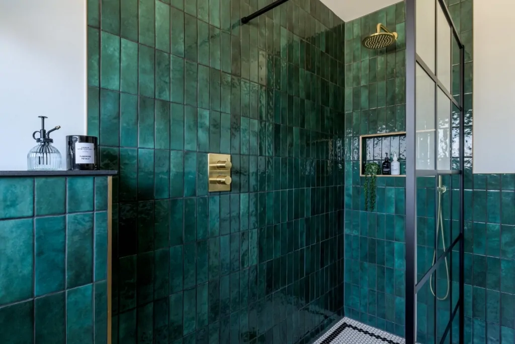 Contemporary shower area with deep green tiles and brass fittings