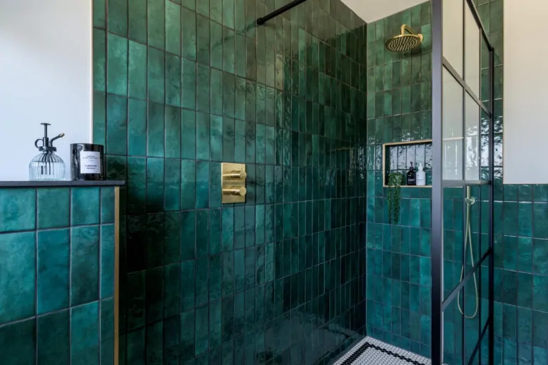 Contemporary shower area with deep green tiles and brass fittings