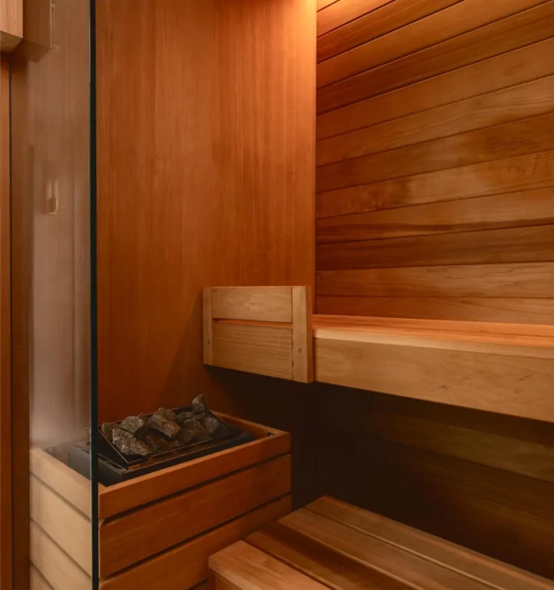 Luxury home sauna with timber walls, bench seating and warm lighting