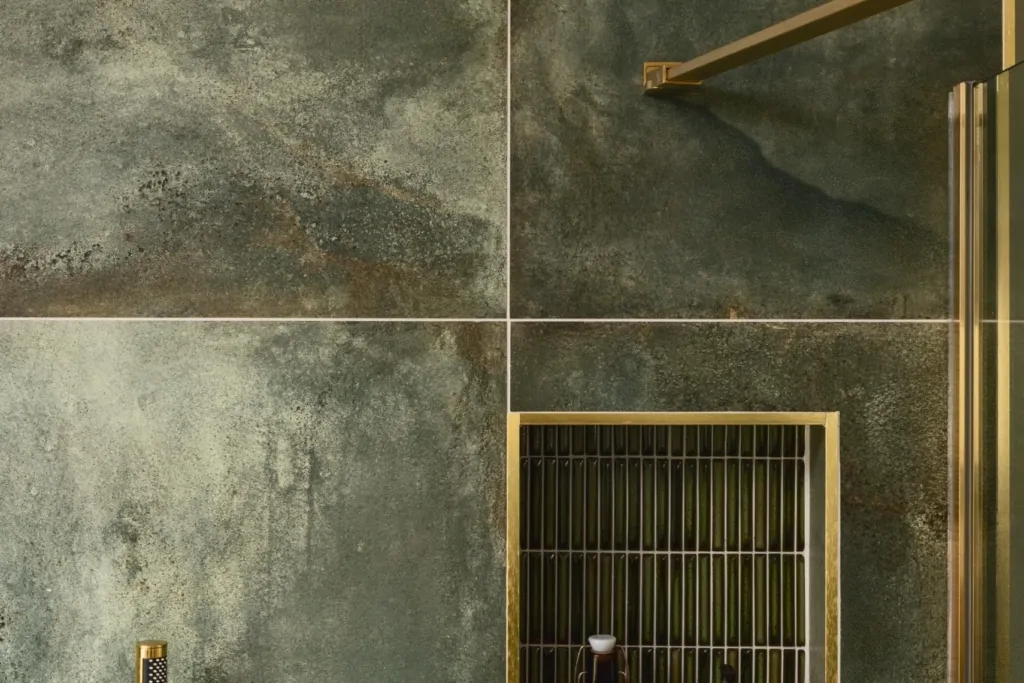 Green stone effect bathroom tiles with recessed shower niche and brass details