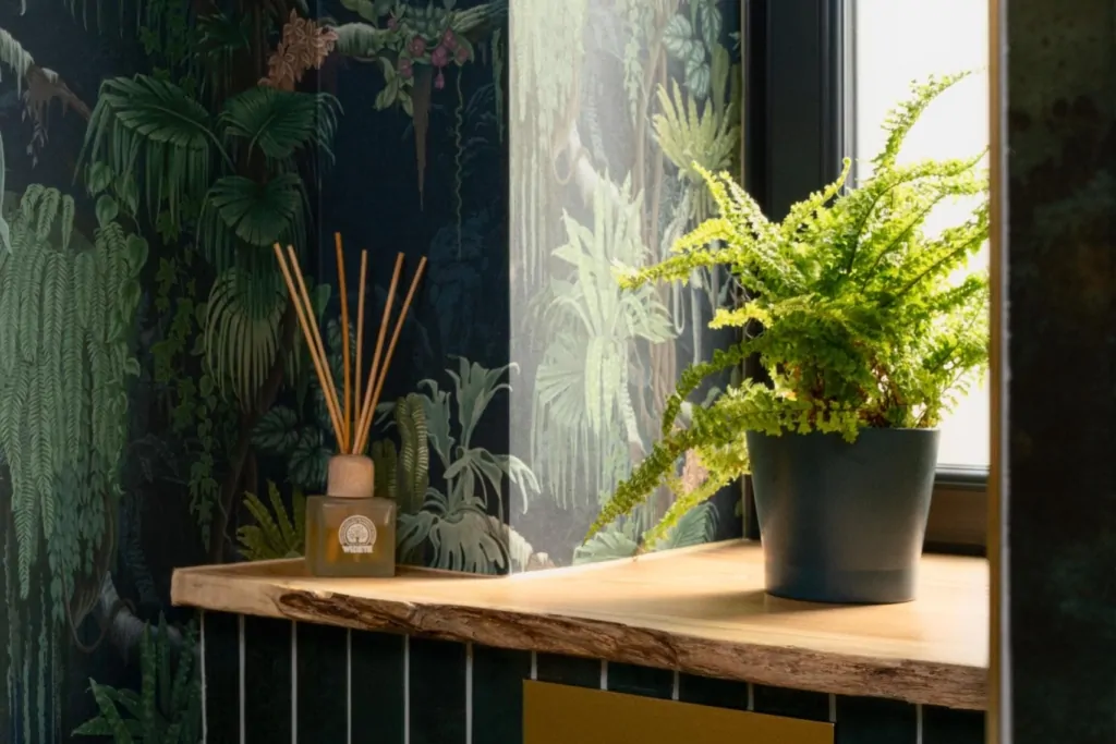 Botanical bathroom design with dark wallpaper, greenery and natural light