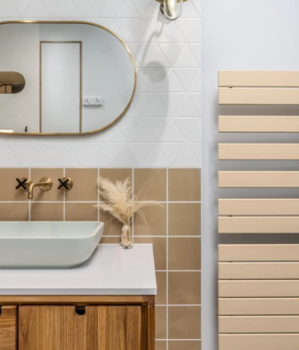 Neutral bathroom vanity with mirror, gold fittings and heated towel rail