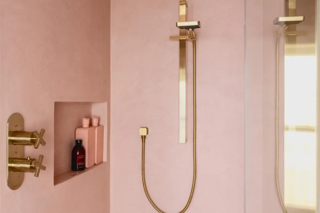 Pink tiled shower area with brushed brass shower fittings