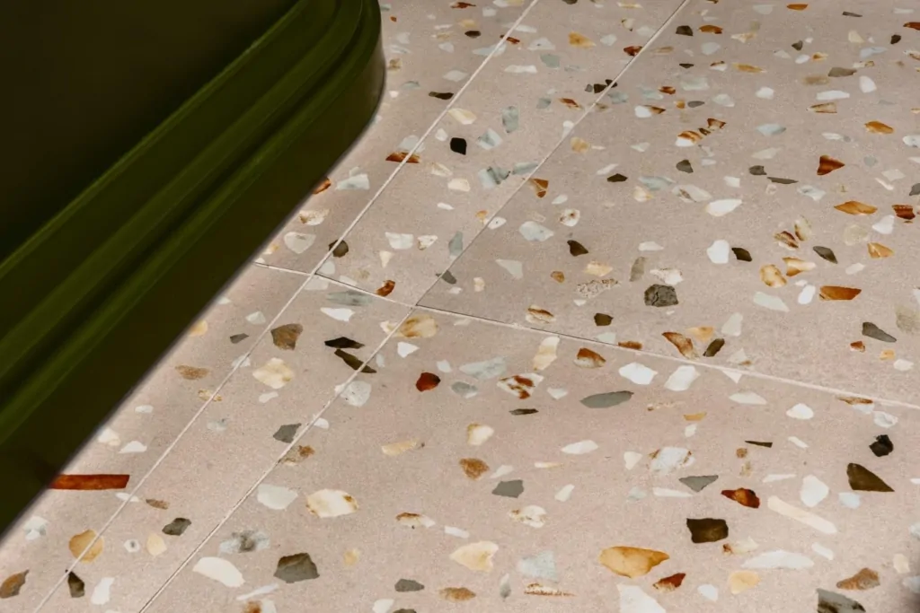 Terrazzo bathroom floor tile with natural stone chips and green border