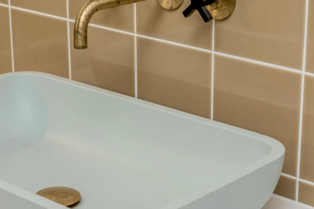 Luxury bath with brushed gold wall-mounted taps and beige tiled surround