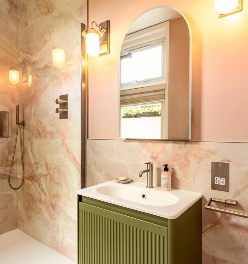 Soft pink luxury bathroom with arched mirror, vanity and brass fittings