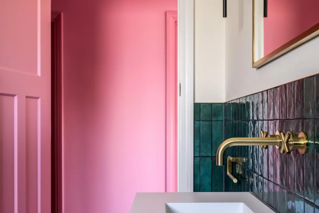 Bold pink doorway leading into a contemporary green tiled bathroom