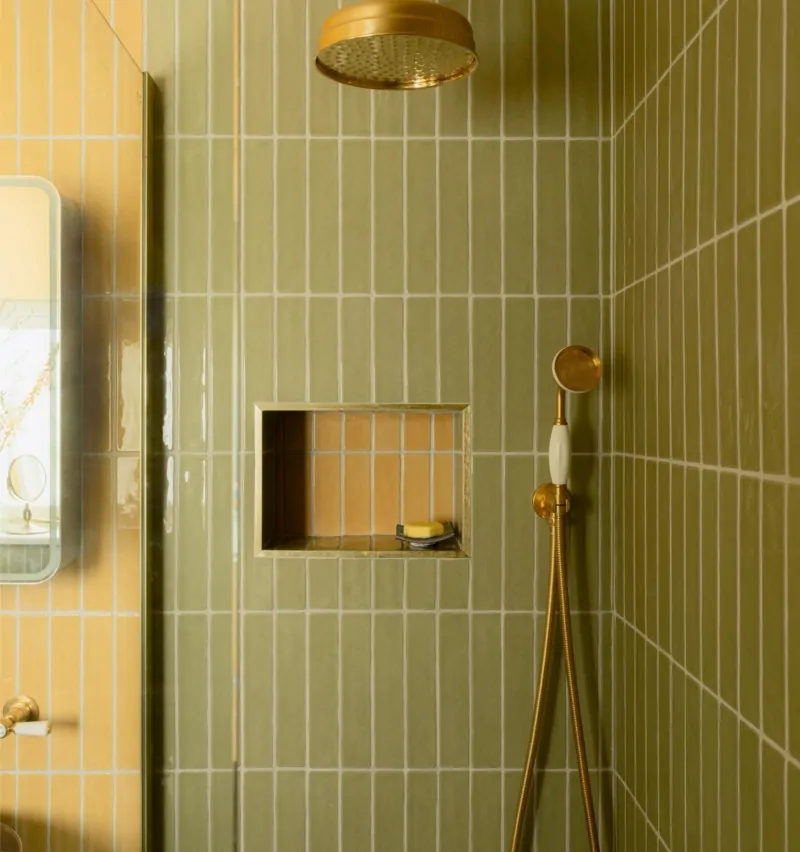 Olive green tiled shower with recessed niche and brass shower fittings