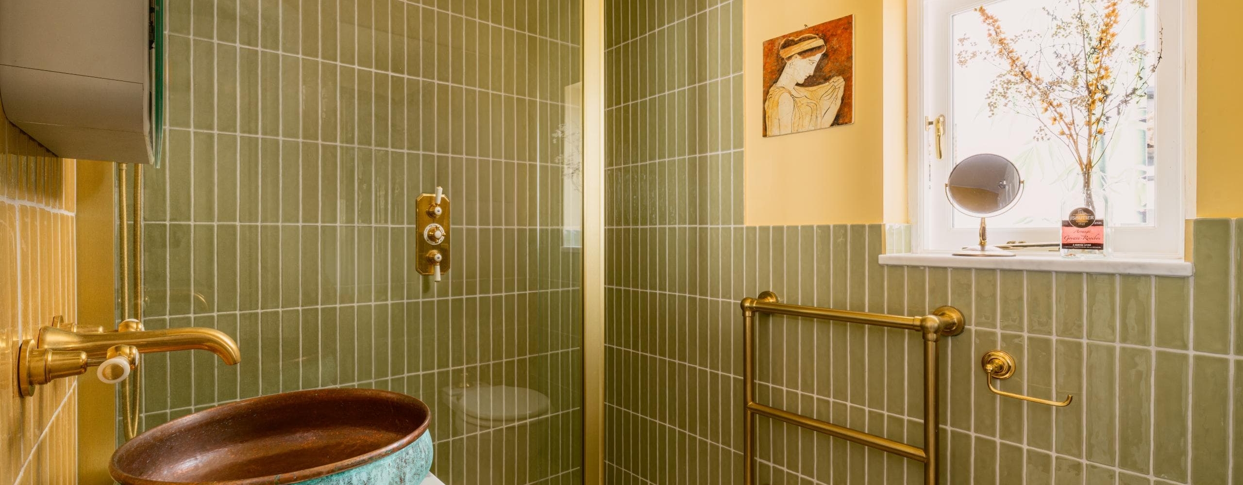 Contemporary shower with slim green tiles, brass fittings and framed artwork
