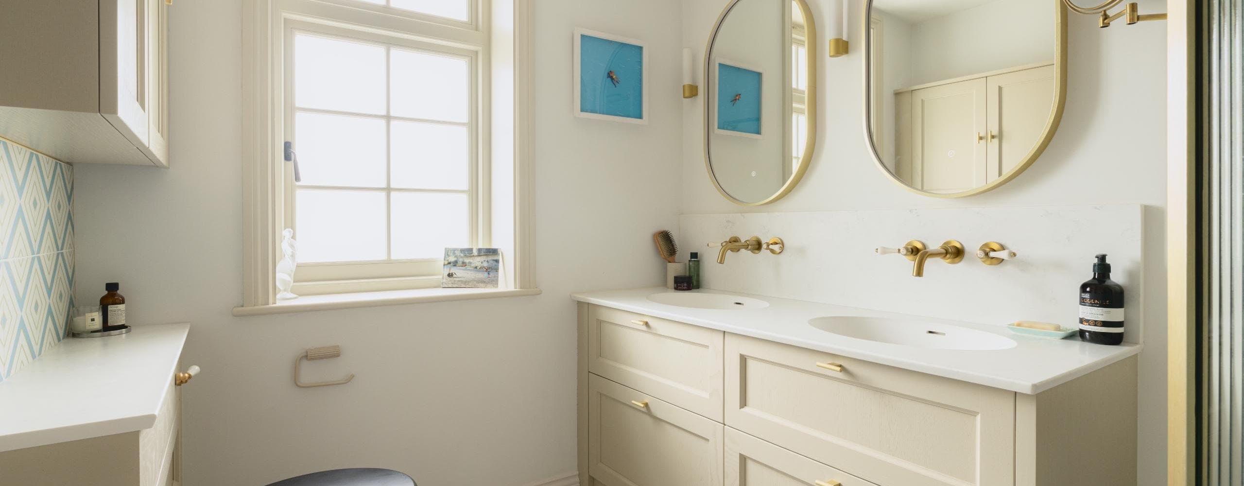 Double bathroom vanity with round mirrors, white cabinetry and brass taps