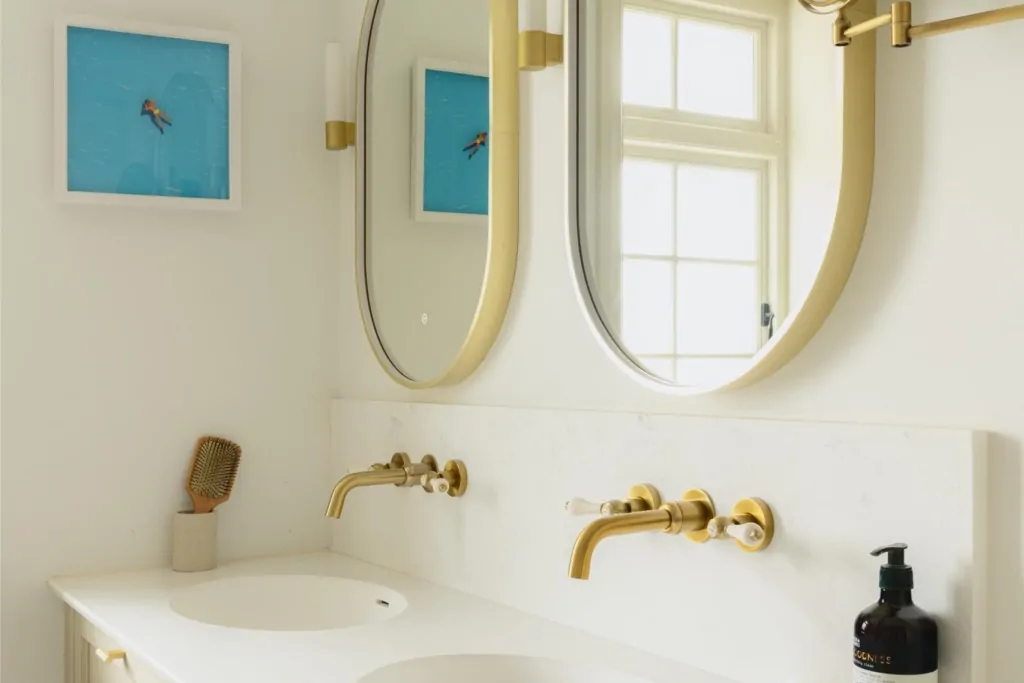 White bathroom vanity with round mirrors and brushed brass wall-mounted taps