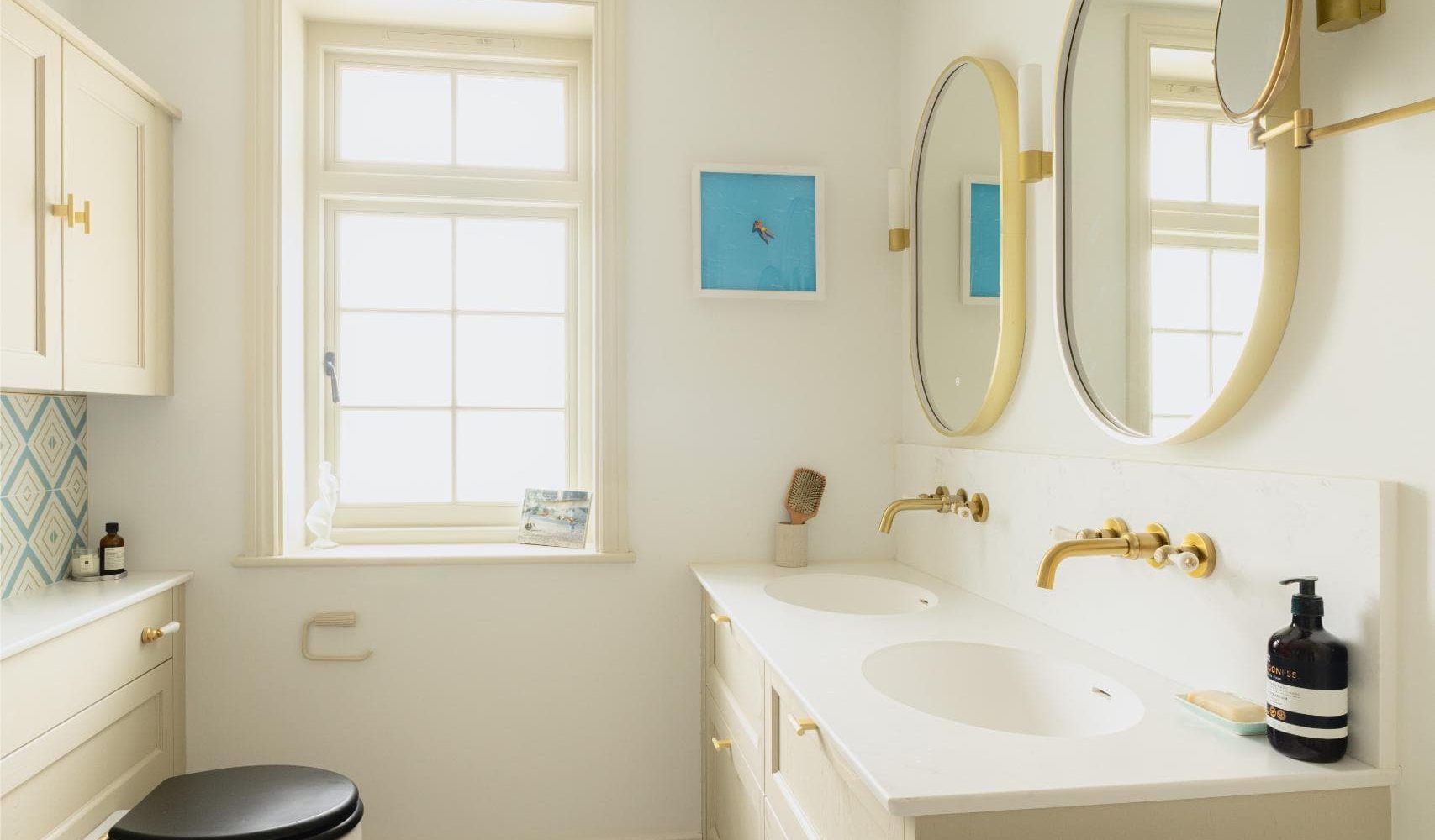 Bright white bathroom vanity with round mirrors and brass fittings