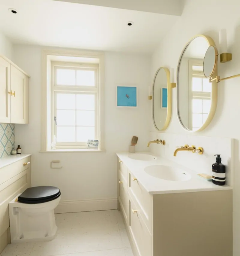 Bright white bathroom vanity with round mirrors and brass fittings