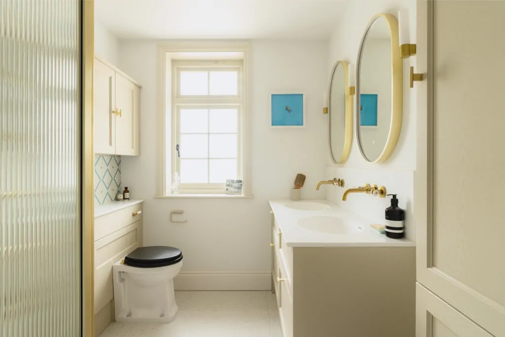Bright double vanity bathroom with round mirrors, white cabinetry and natural light