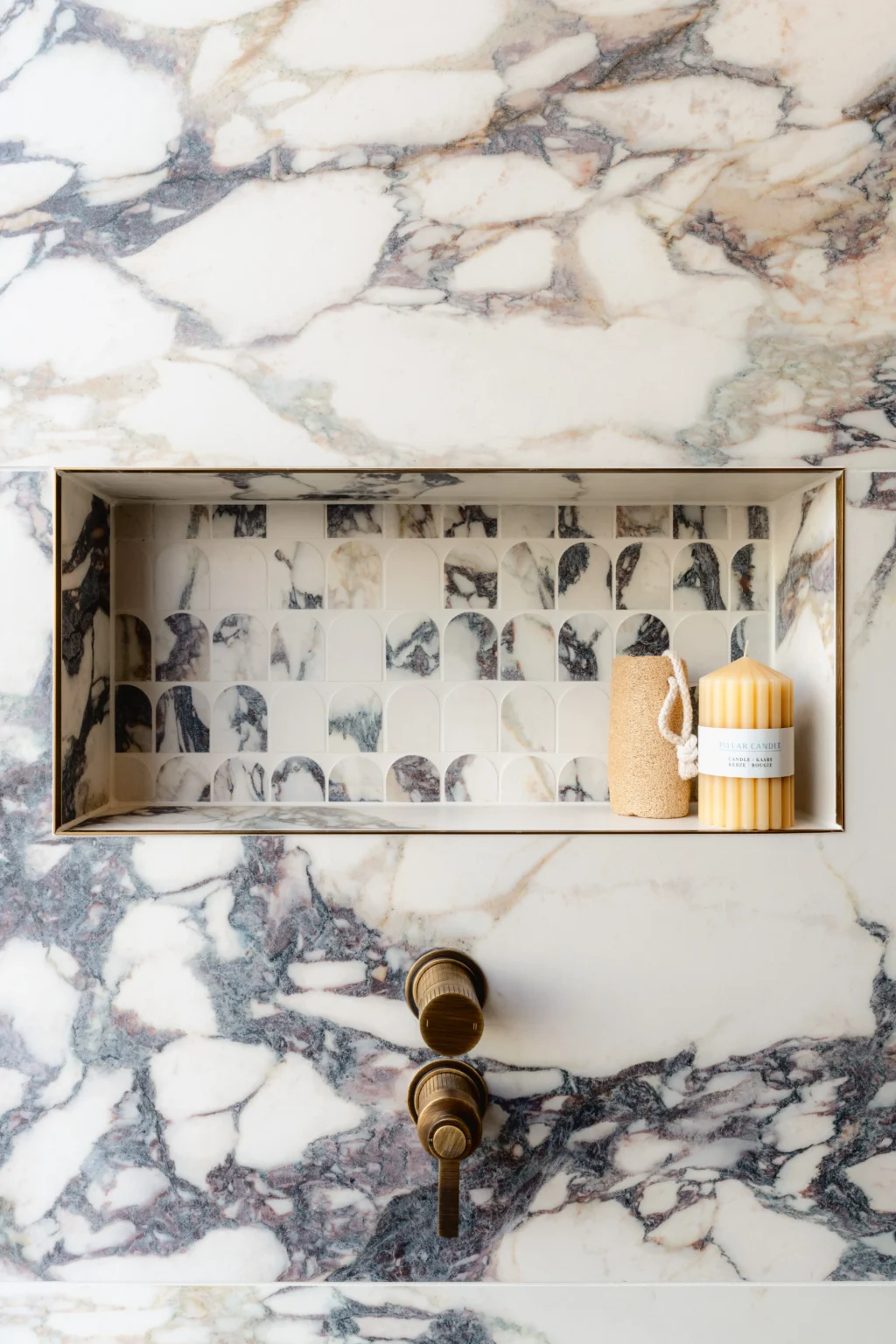 Modern bathroom showroom display featuring patterned tiles, brass fittings and a walk-in shower enclosure