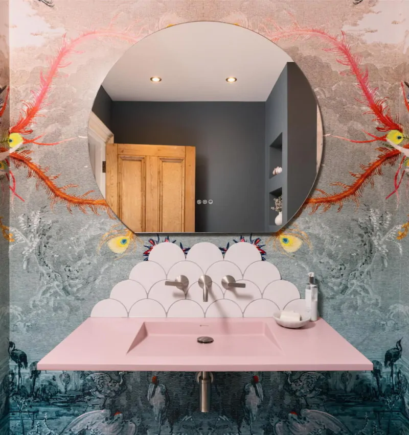 Round illuminated bathroom mirror against a dramatic artistic feature wall