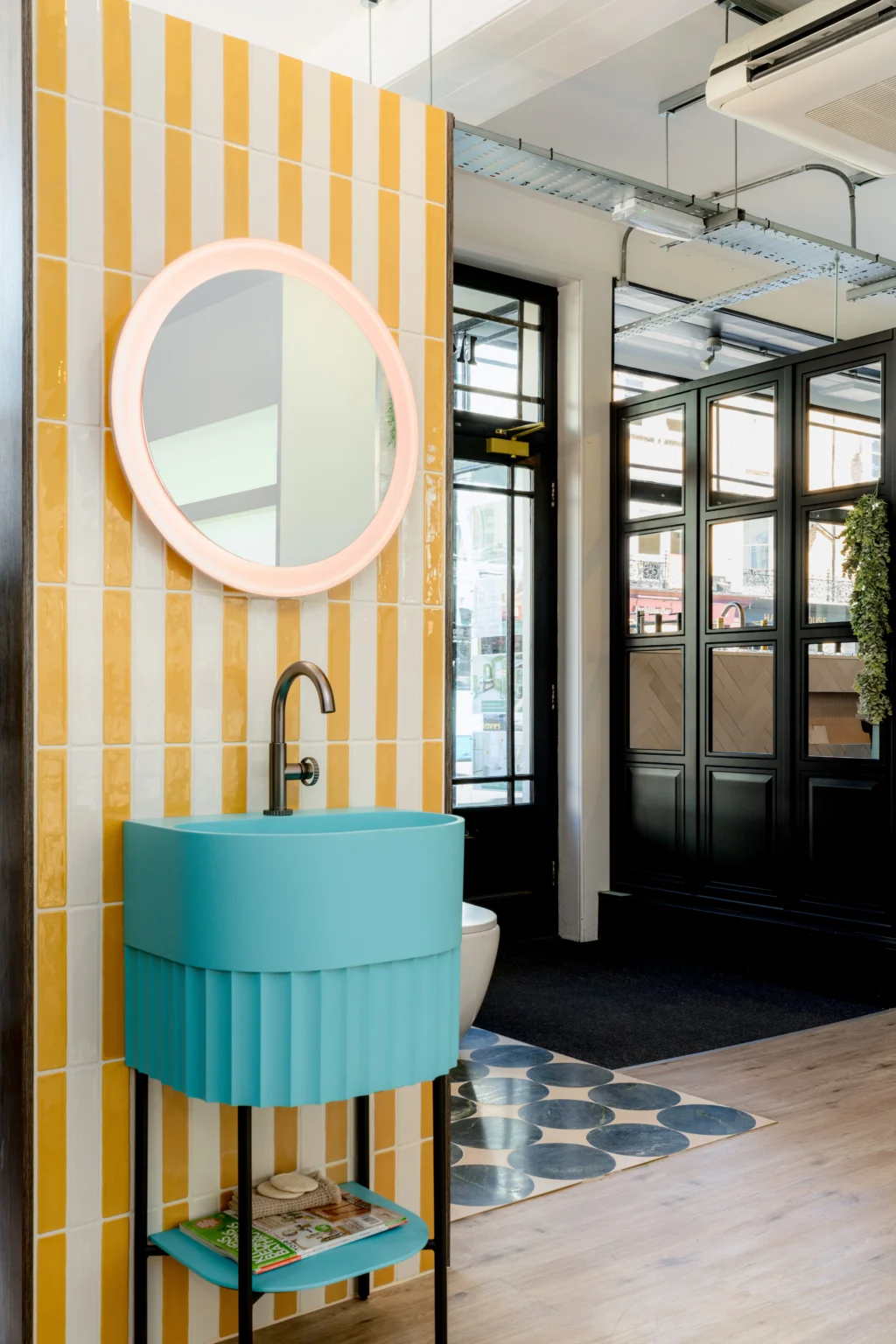 Contemporary bathroom showroom display featuring a vanity unit, circular mirror and premium bathroom fittings