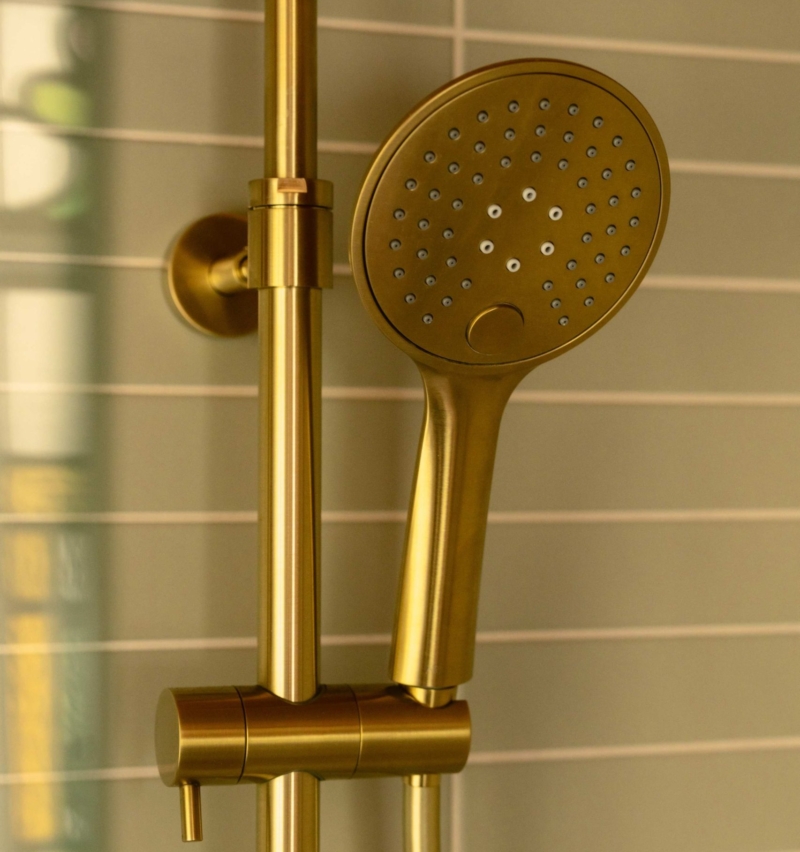 Brushed brass handheld shower and controls against sage green tiles in the Clementine family bathroom in Hove.