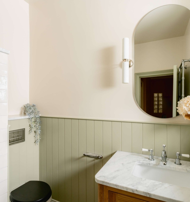 Elegant Hove family bathroom with oak vanity, marble surfaces, sage panelling, polished chrome fittings and basketweave flooring.