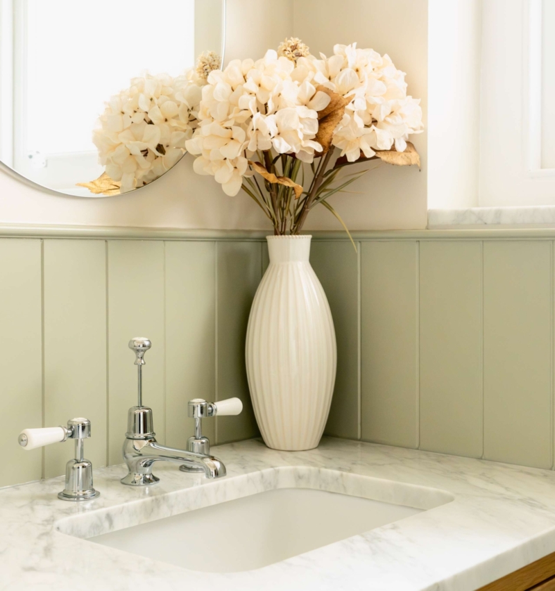 Marble basin with traditional polished chrome Burlington taps, framed by soft sage wall panelling and a light oak vanity.